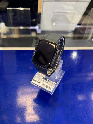 Black smartwatch on a clear stand with a blue surface and blurred background