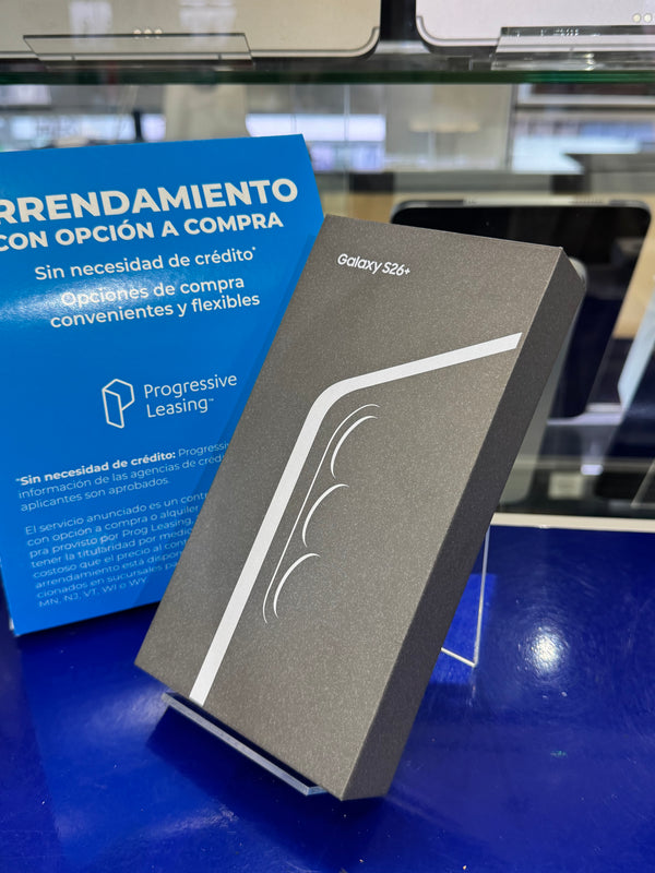 Samsung Galaxy S24+ smartphone box in dark gray packaging with a white curved stripe design, standing on a display stand on a blue counter next to a blue leasing offer card.
