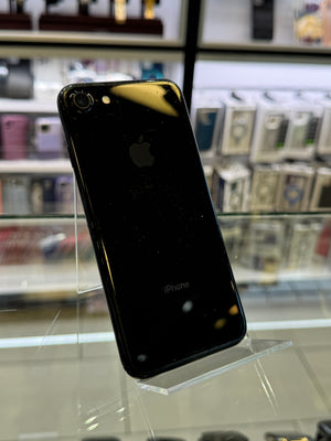 Black smartphone on a stand with shelves of phone cases in the background