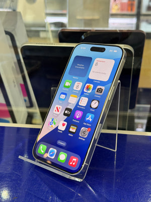 A silver Apple iPhone with a colorful front display mounted on a clear acrylic stand inside a retail display case.