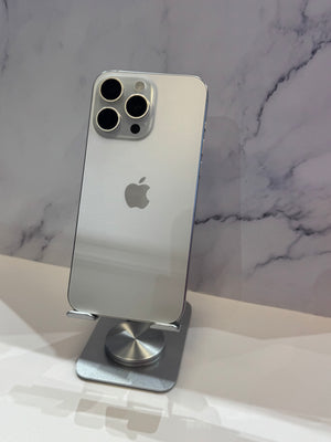 A silver Apple iPhone Pro with a glass back and triple rear camera system, standing upright on a metallic stand against a white and gray marble-patterned background.