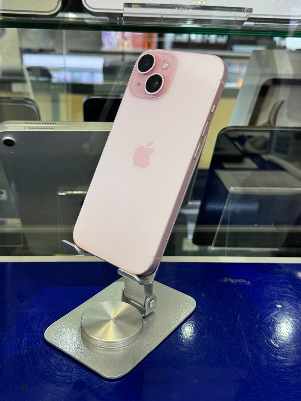 A light pink Apple iPhone 13 Pro displayed on a silver metal stand inside a retail store, with glass cases and other devices blurred in the background.