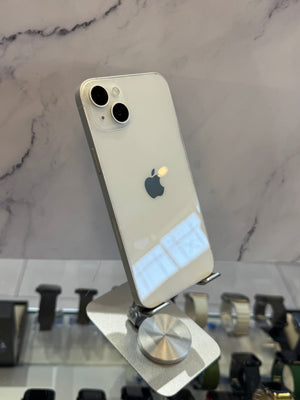 A white Apple iPhone 12 Pro shown from the back, resting on a metallic stand in front of a marble-patterned background.