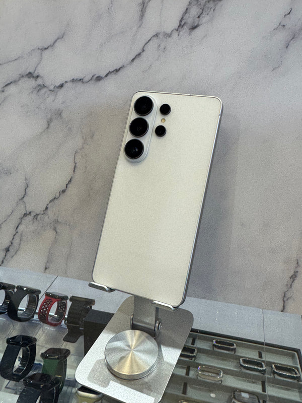 A silver Samsung Galaxy Ultra smartphone shown from the back, mounted on a metal display stand in a retail setting against a gray marble-patterned wall.