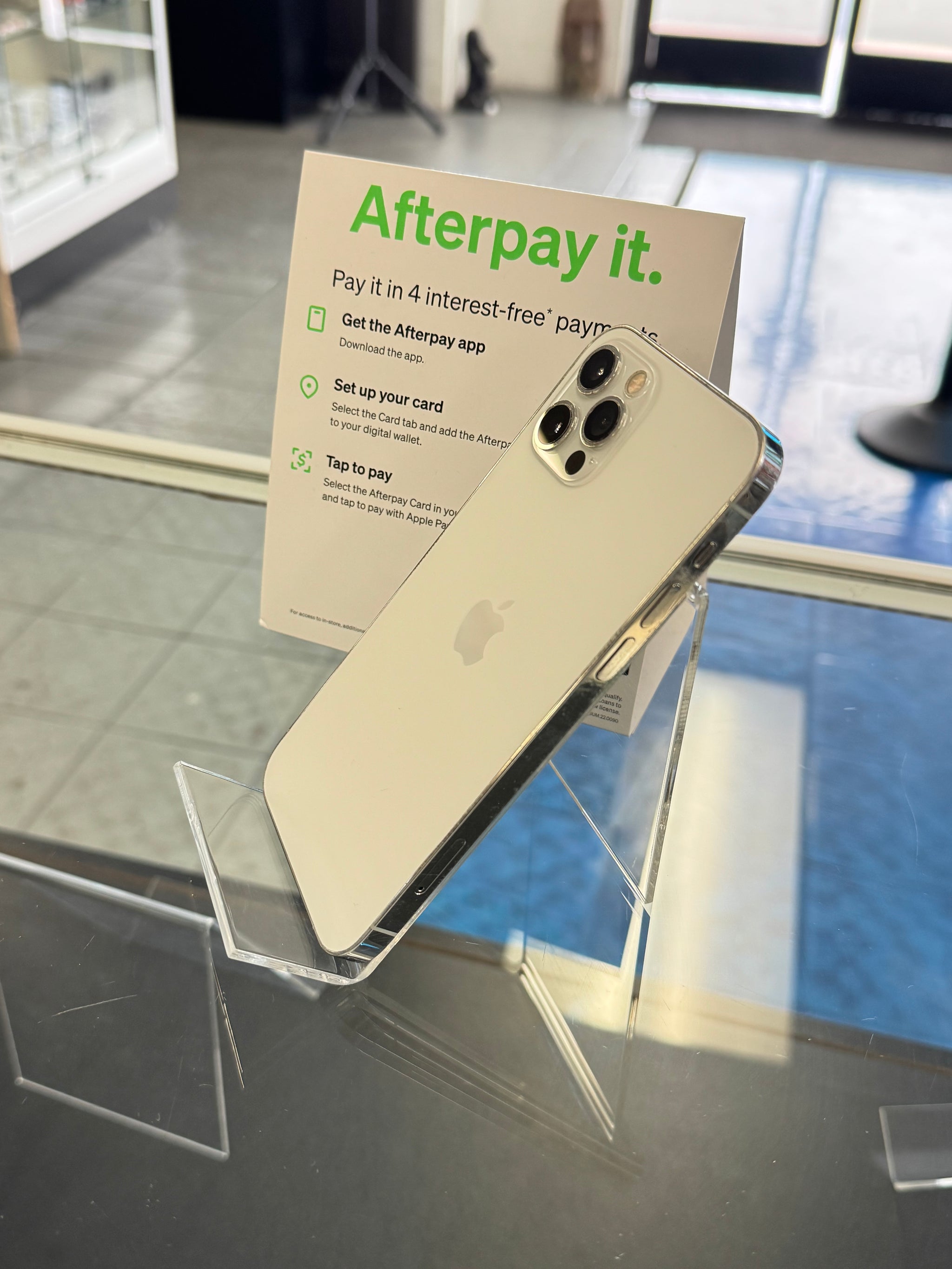 Gold smartphone on a stand with 'Afterpay' promotional sign in the background