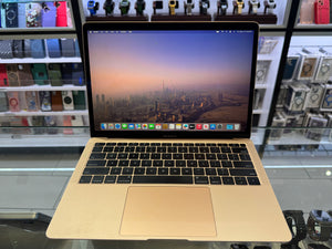 Apple laptop on a glass table with a cityscape on the screen, surrounded by electronic products.