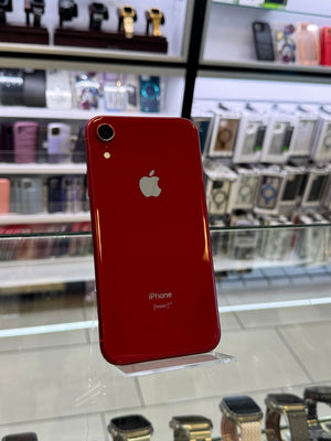 Red Apple smartphone on a reflective surface with blurred store interior in the background