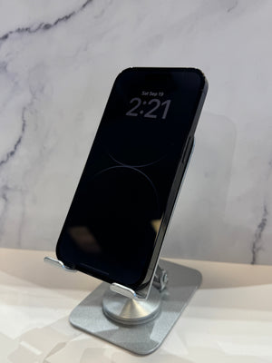 A black smartphone displayed upright on a silver metal stand against a light marble-patterned background.
