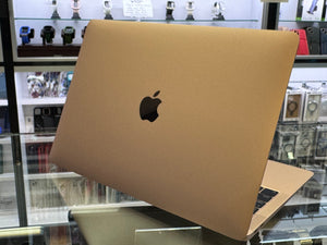 Gold laptop with Apple logo on a glass display case background
