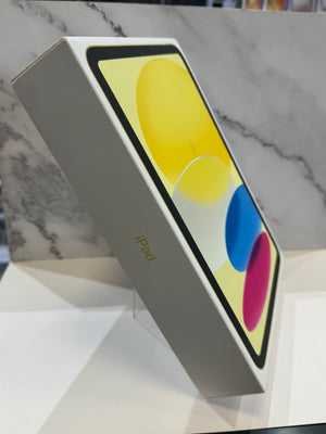 An Apple iPad box standing upright on a white surface, with a marble-patterned background and the iPad screen graphic visible on the box front.