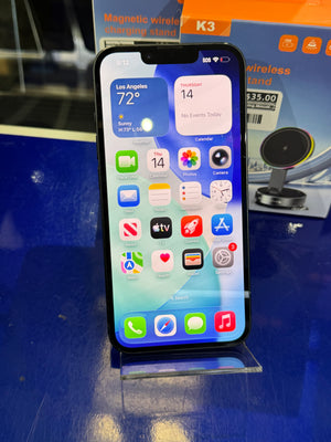 Smartphone with app icons displayed on a blue surface with a charging stand in the background.