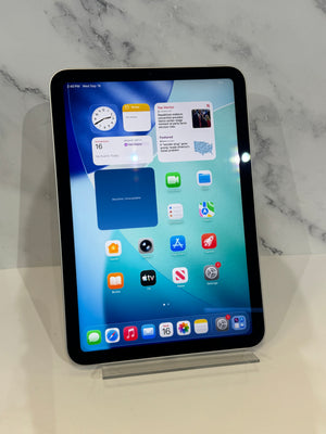 A black iPad Pro 10.9 standing upright on a clear acrylic display stand against a white marble-patterned background.