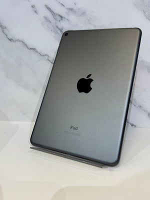 A gray Apple iPad shown from the back, resting on a clear stand against a white marble-patterned background.