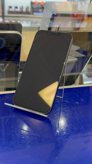 A black smartphone with a blank screen, displayed upright on a clear stand on a blue counter inside a store.