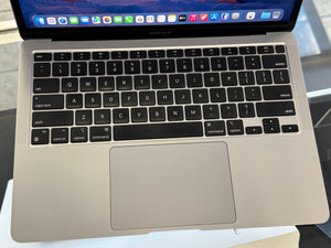 Close-up of a laptop keyboard and trackpad on a reflective surface
