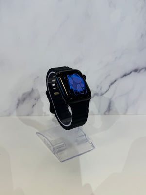 A black smartwatch with a black band and a blue watch face, displayed on a clear acrylic stand against a white marble-patterned background.