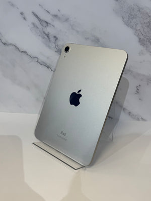 A silver Apple iPad standing upright on a clear acrylic display stand against a white marble-patterned background.