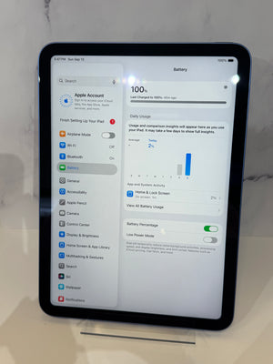 An iPad displaying the Apple Settings screen for Battery on a light countertop against a white marble-look background.