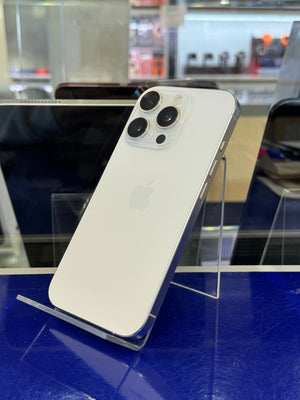 A white Apple iPhone with a silver bumper frame, shown from the back, resting on a clear acrylic display stand in a retail or showroom setting.