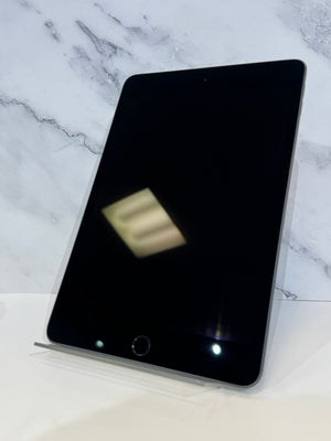 A black tablet device with a silver edge, resting on a clear acrylic stand against a white marble-patterned background.