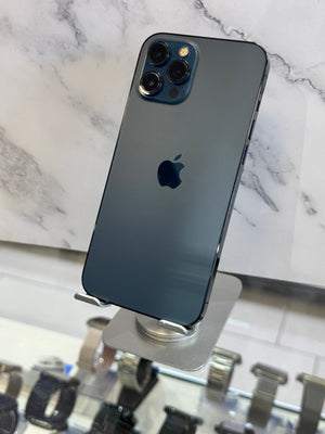 A dark blue-gray Apple iPhone Pro shown from the back, mounted on a small display stand in front of a marble-patterned background.
