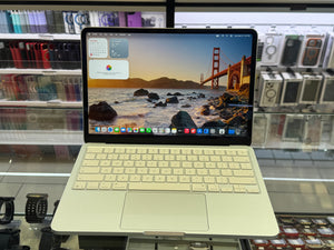A silver aluminum laptop with a matching keyboard cover and trackpad, shown open with its screen on in a retail display setting.