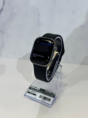 Black Apple watch series 11 displayed on an acrylic stand showing a label against a marble background. 