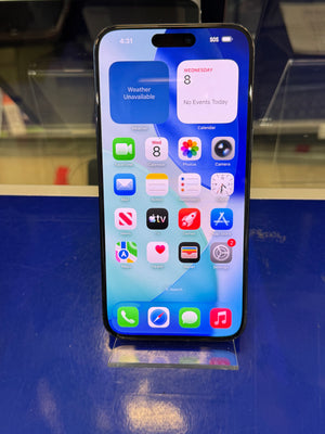 A black smartphone with a large front display showing the home screen, photographed from above on a blue surface.