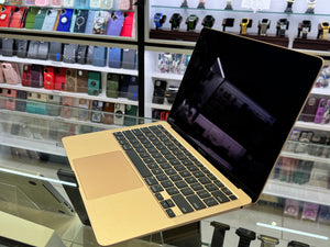 Gold laptop on a glass table with shelves of products in the background