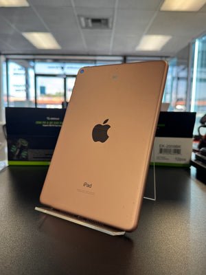 An Apple iPad in rose gold, showing the back of the device with the Apple logo and 'iPad' text, resting on a display stand in a retail or showroom environment.