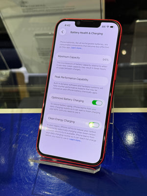 Smartphone displaying battery health and charging settings on a reflective surface