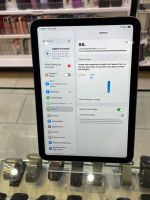 A tablet device shown from the side with its screen on, displaying a settings interface, photographed in a retail or display environment.