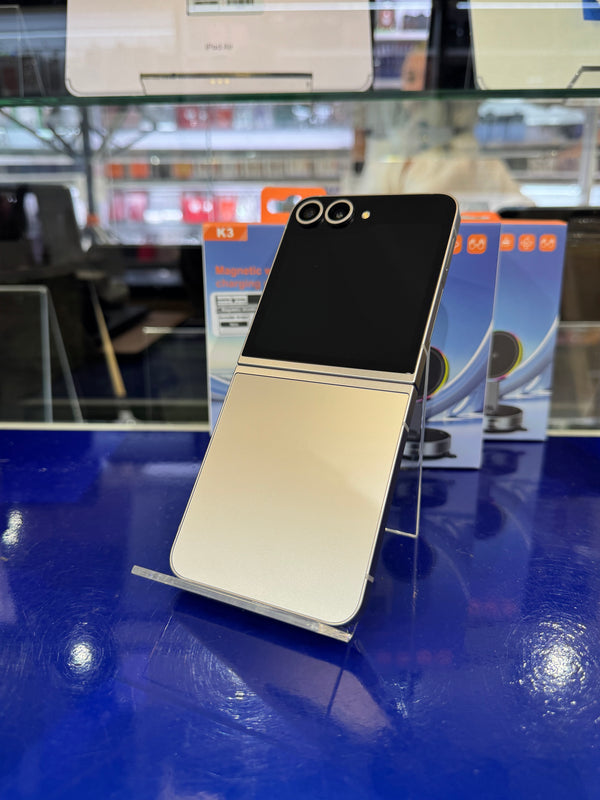Two toned smartphone displayed on a blue stand with blurred store interior.
