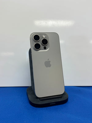 An Apple iPhone with a silver aluminum back, resting on a black display stand against a white background with a blue surface below.