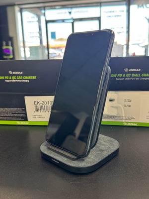 A black smartphone resting on a gray felt-lined charging dock, with a Google-branded box in the background.