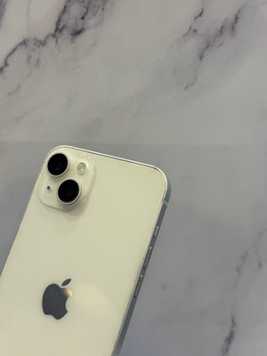 A close-up of the back of a white Apple iPhone with two rear cameras, resting on a white and gray marble surface.
