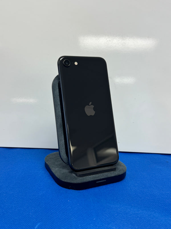 A black Apple iPhone 8 shown from the back, resting on a dark gray stand against a white background with a blue surface below.