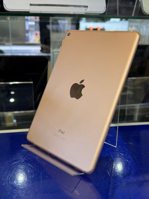 Gold iPad on a blue surface with a blurred background