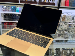 Gold laptop on a glass surface with shelves in the background