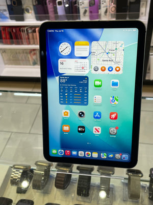 A black tablet with a colorful home screen displayed inside a retail store glass case.