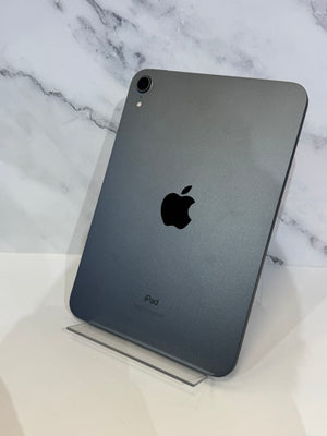 A dark gray Apple iPad standing upright on a clear acrylic display stand against a white marble-patterned background.