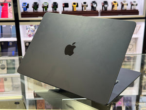 Black Apple laptop on a glass surface with a blurred store background