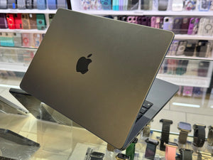 Apple laptop on display in a store with various products in the background