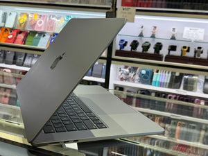 Silver laptop on a reflective surface with shelves of products in the background