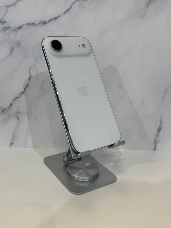 A silver Apple iPhone with a white back is displayed on a metallic silver stand against a white marble-patterned background.