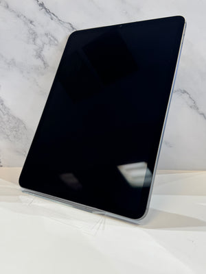 A black tablet with a silver edge, shown standing at an angle on a white surface against a white marble-patterned background.