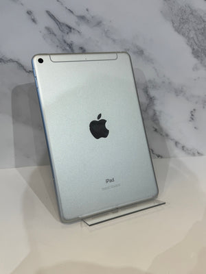 A silver Apple iPad shown from the back, resting on a clear acrylic stand against a white marble-patterned background.