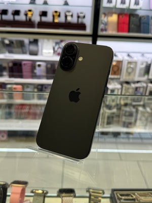 Black smartphone with Apple logo on a glass surface with blurred shelves in the background