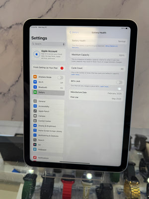 An iPad displaying the Settings app, with the Battery Health page visible, photographed upright on a display stand against a marble-patterned background.