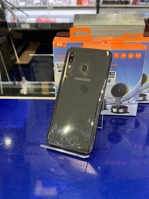 Black Samsung smartphone on a stand with a blue surface and product packaging in the background